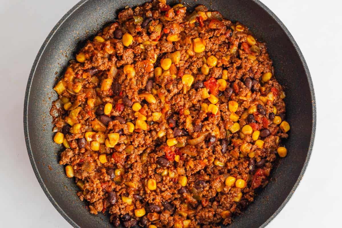 cooking ground beef, corn and black beans in skillet with salsa.