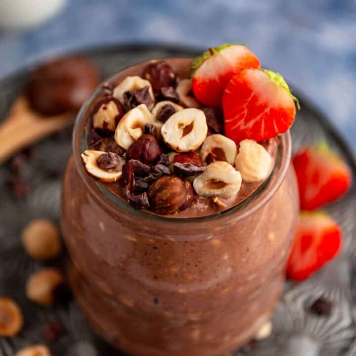 chocolate overnight oats with hazelnuts and strawberries in mason jars.