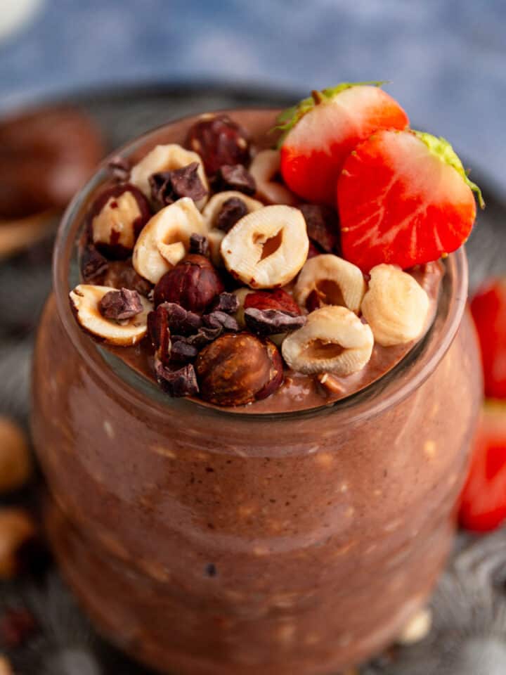 chocolate overnight oats with hazelnuts and strawberries in mason jars.