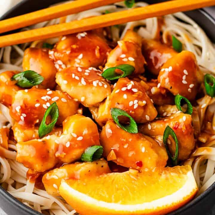 orange chicken with noodles and orange slices.