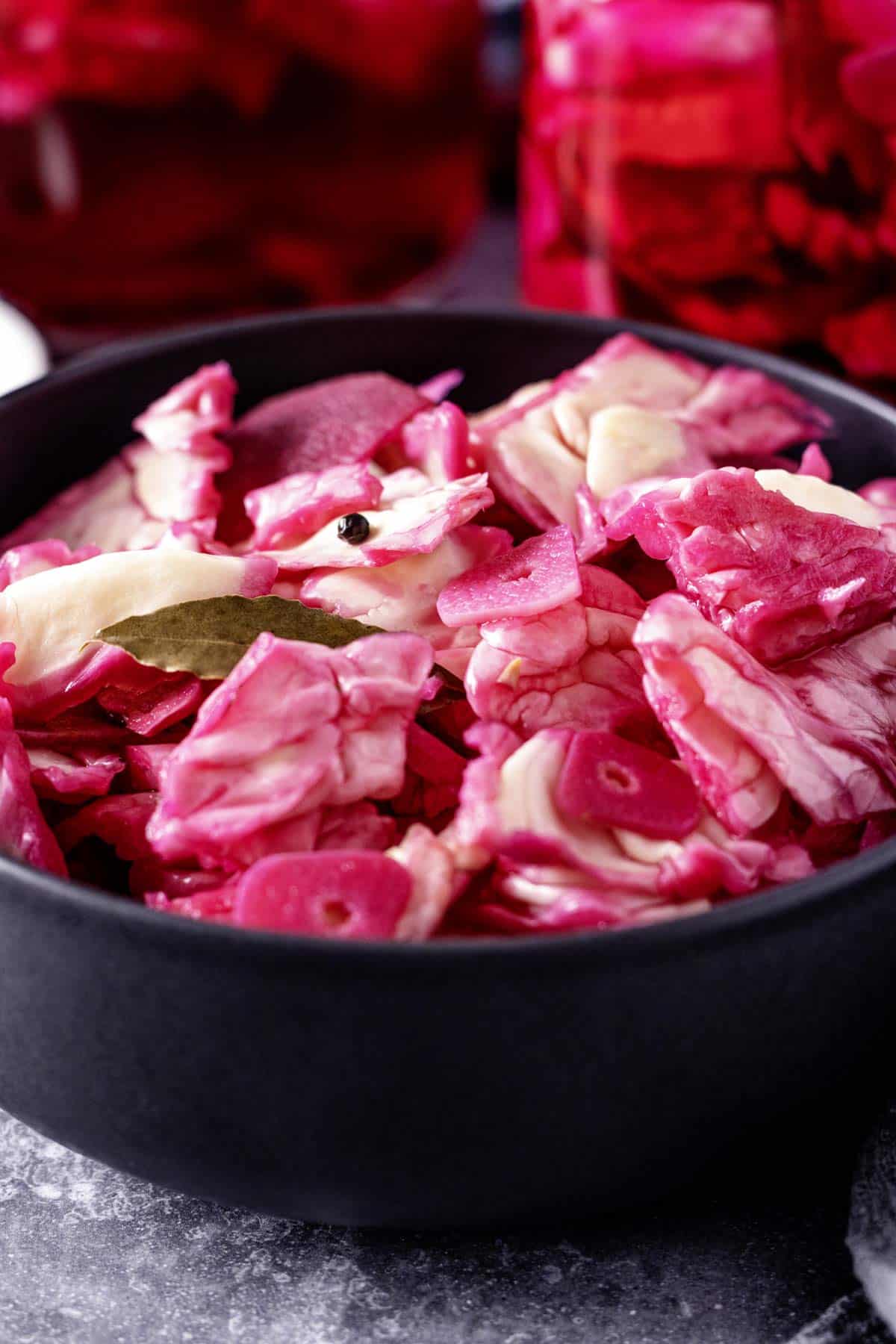 pickled cabbage with beets in a black bowl.