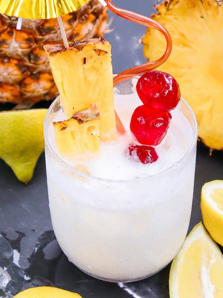 light yellow pina colada cocktail served over ice and with garnishes.