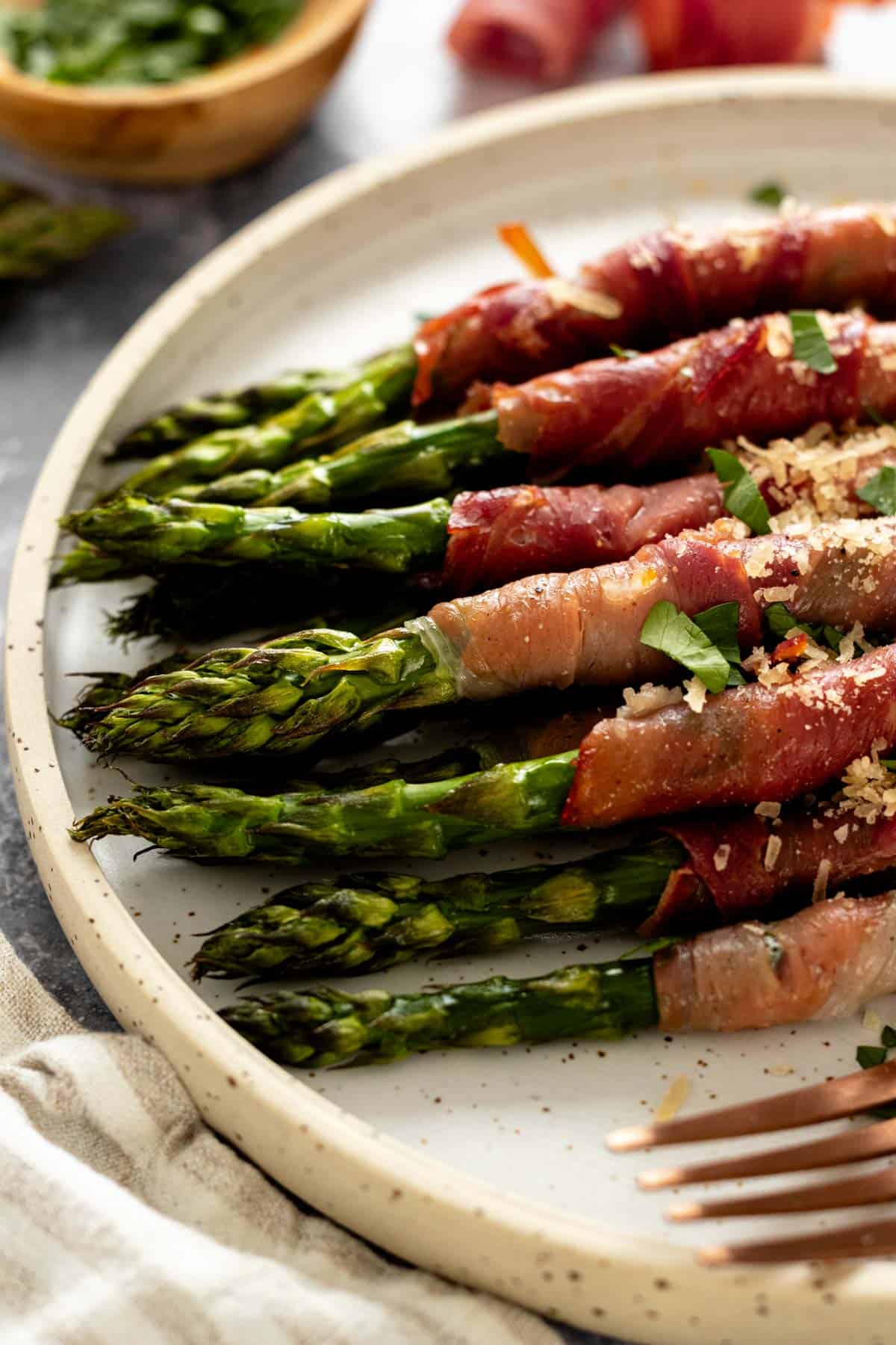 a plate of crispy prosciutto wrapped asparagus with parmesan.