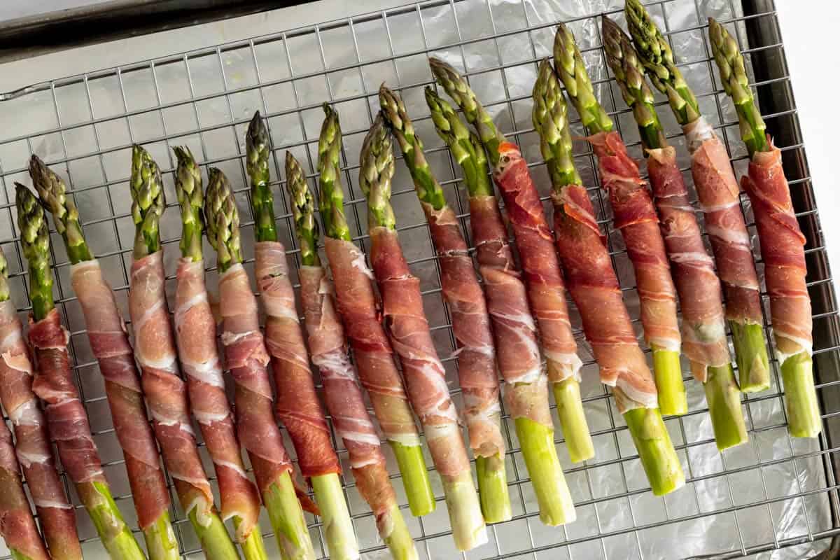 asparagus spears wrapped in prosciutto on a wire rack.