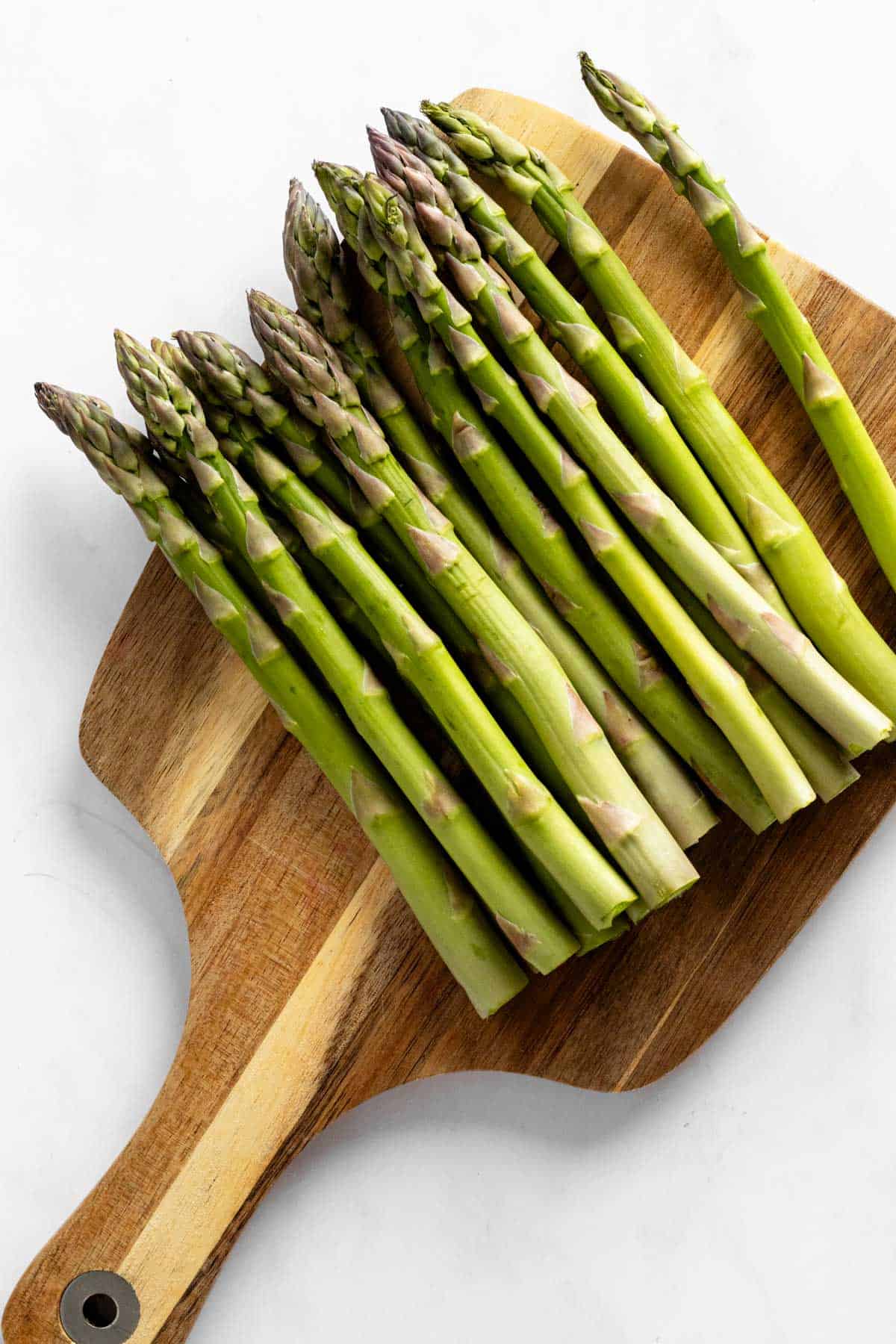 trimmed asparagus spears on a wooden cutting board.