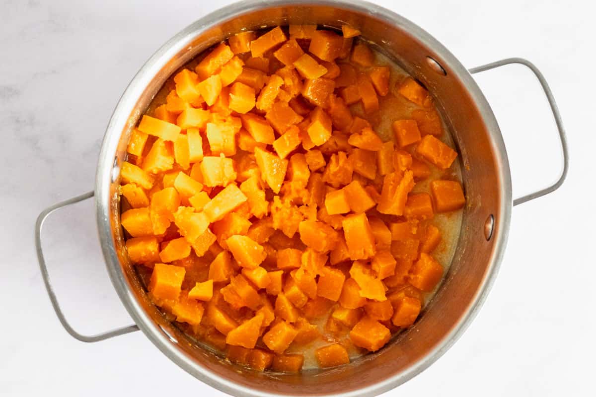 cooked pumpkin pieces with coconut milk in a pot.