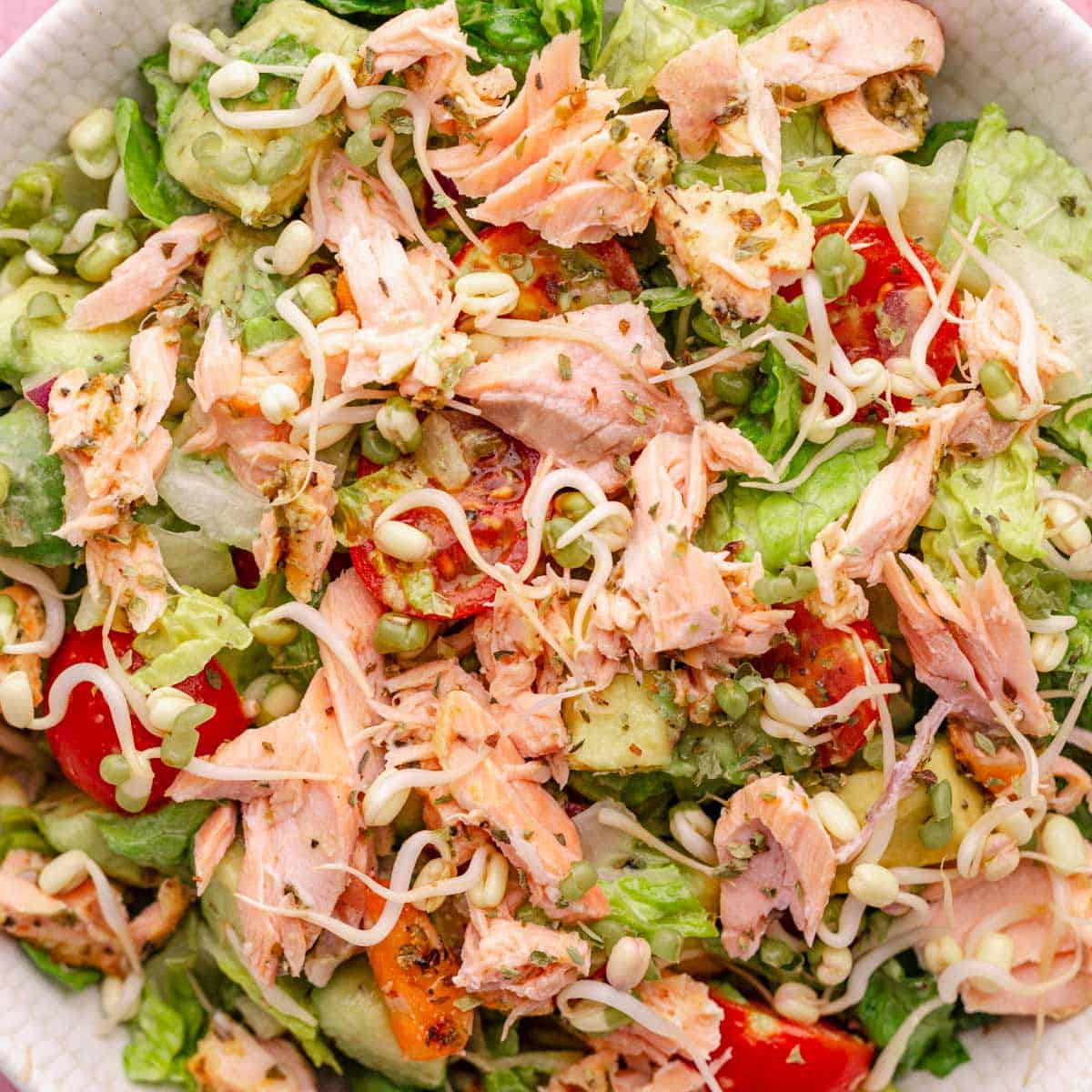 salmon salad bowl in a white bowl with parsley and cabbage