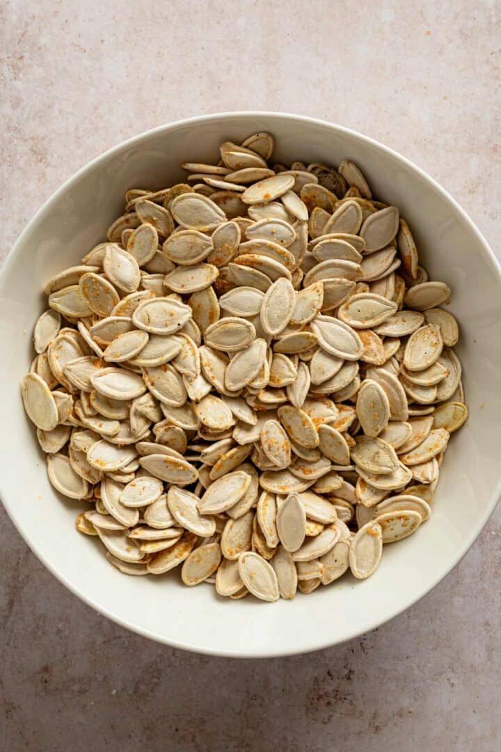 pumpkin seeds tossed in onion powder in a bowl.