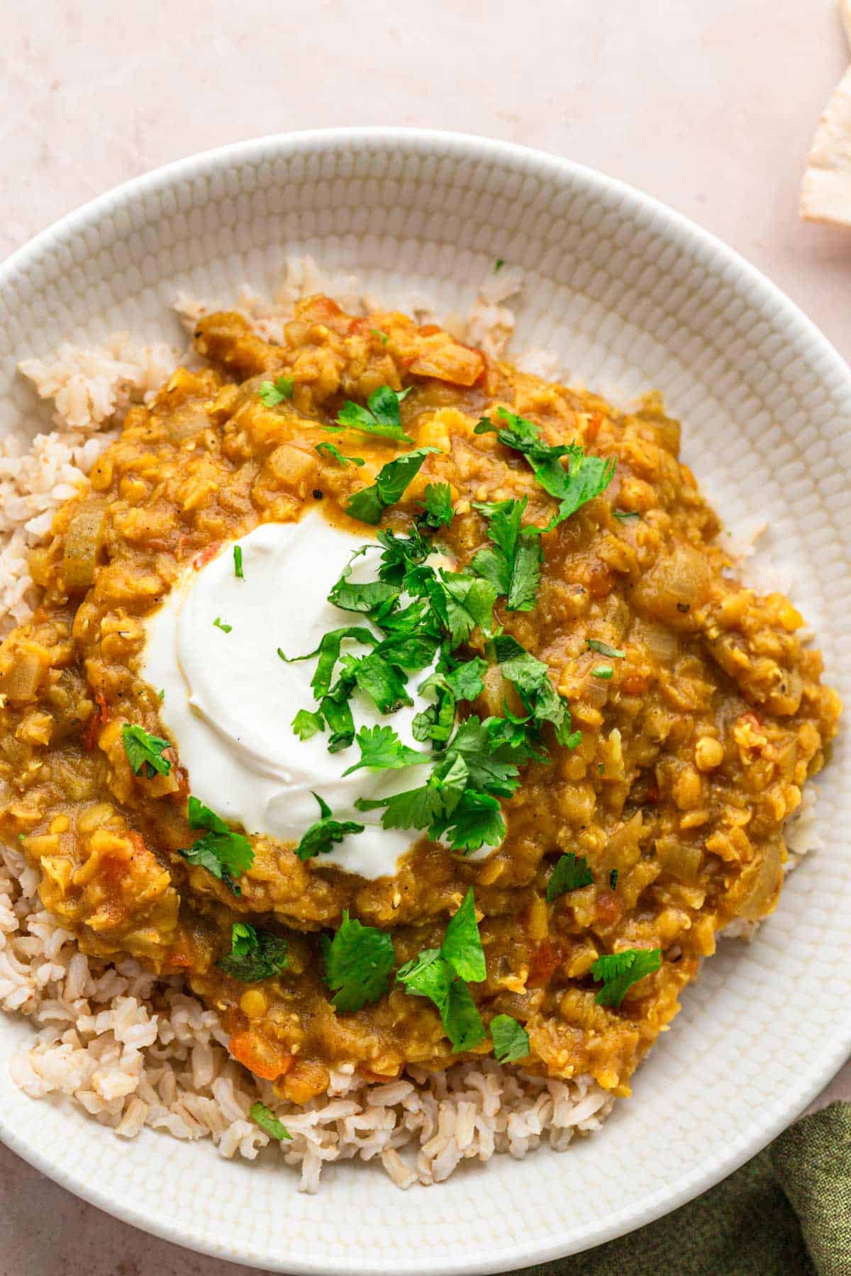 Red Lentil Dhal with cilantro and lime wedges.