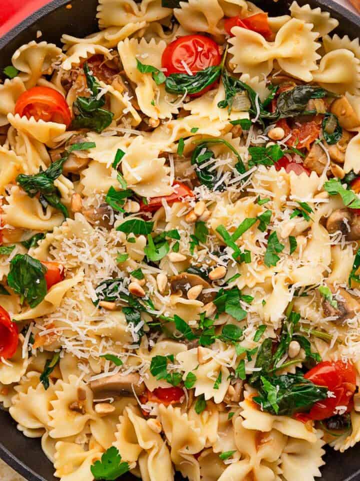 simple spinach tomato pasta in skillet with parmesan.