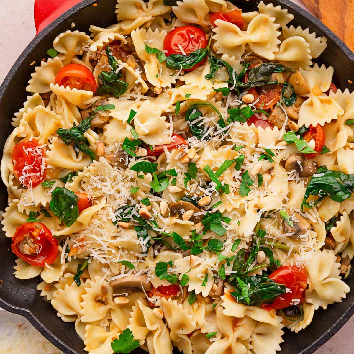 simple spinach tomato pasta in skillet with parmesan.