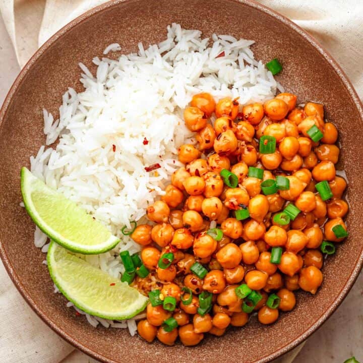 Sticky sesame chickpeas with rice and lime wedges.