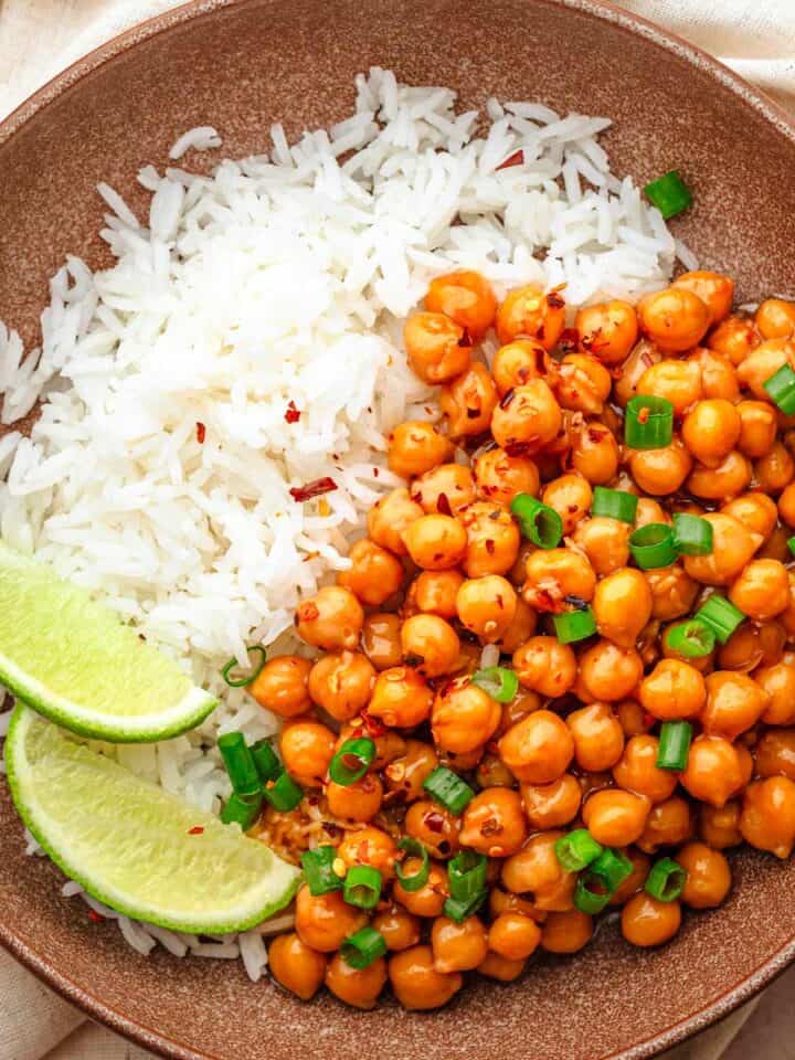 Sticky sesame chickpeas with rice and lime wedges.