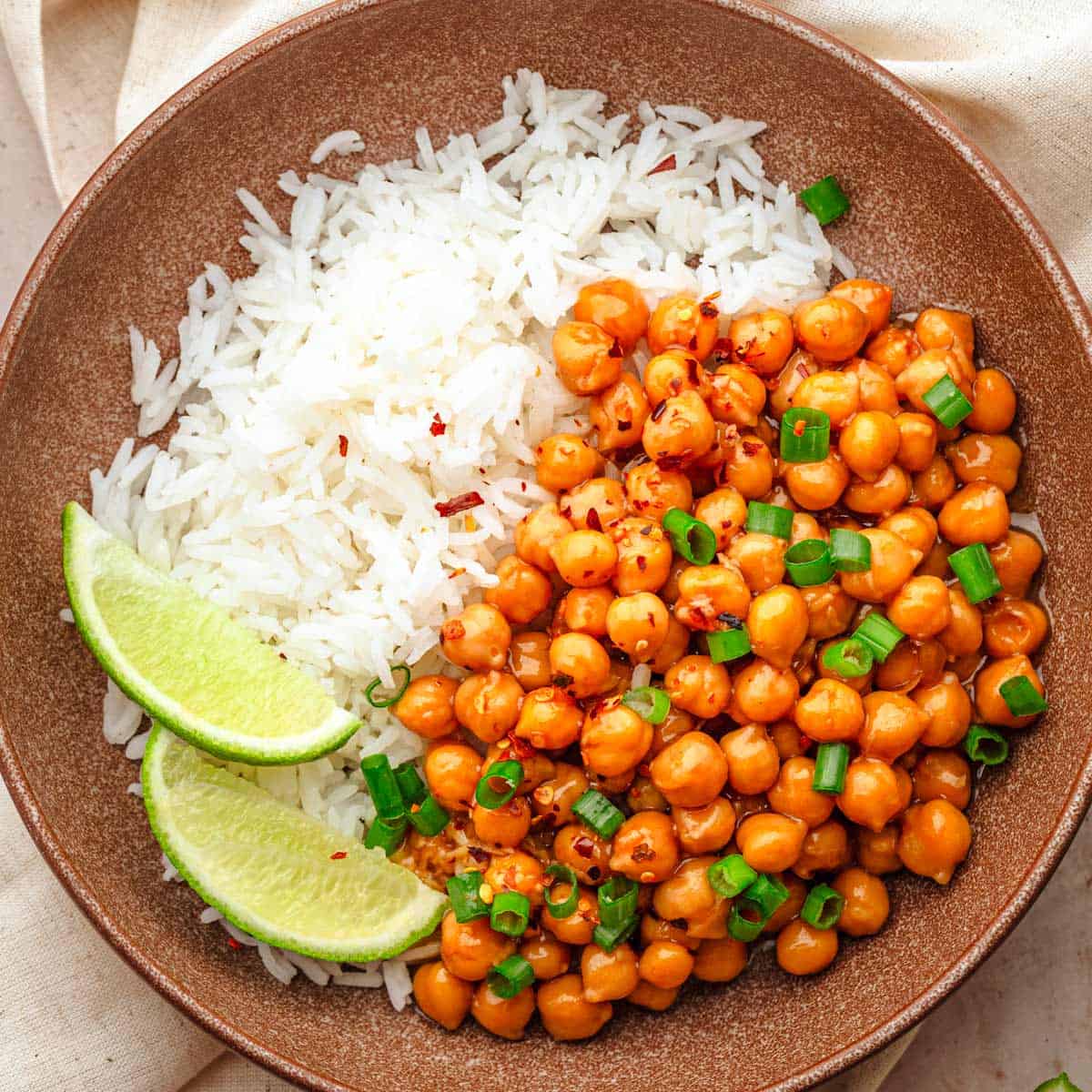 Sticky sesame chickpeas with rice and lime wedges.