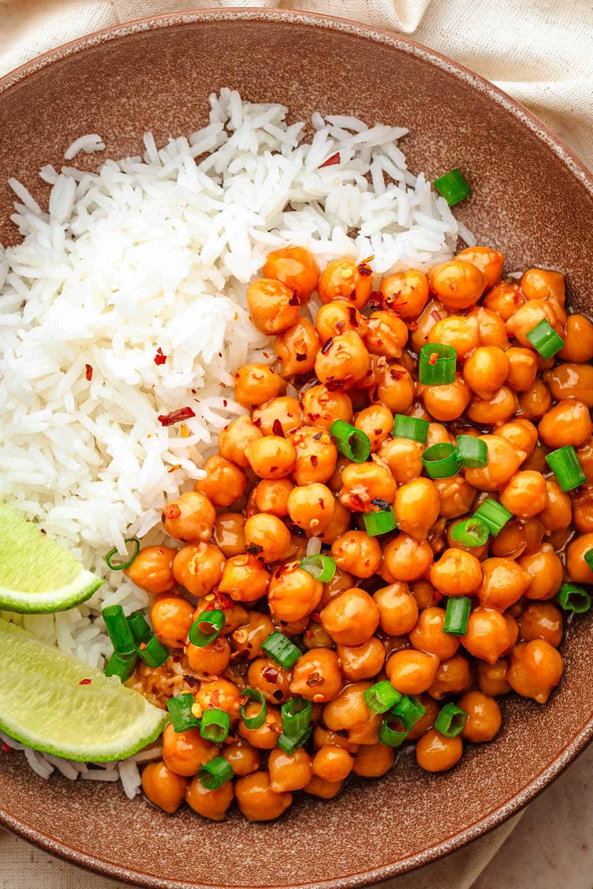Sticky sesame chickpeas with rice and lime wedges.