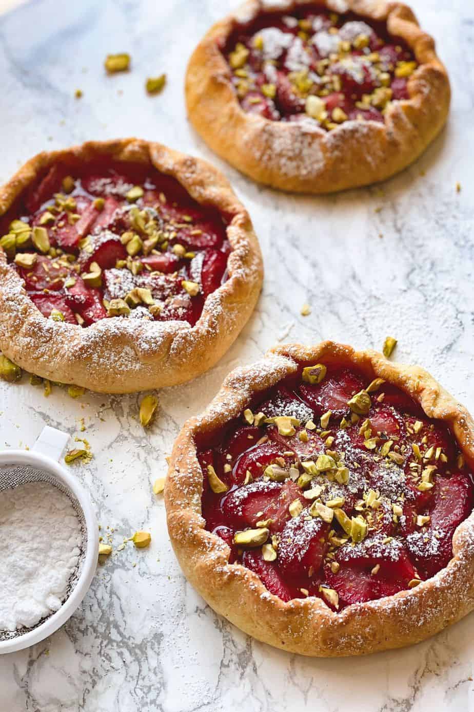 Strawberry pistachio galettes - The easiest and most delicious strawberry dessert recipe. These min yummy strawberry pies are made with cottage cheese, fresh strawberries and topped with crushed pistachios. Simply the best and easiest homemade mini pie recipe that no one cant resist. - The Yummy Bowl