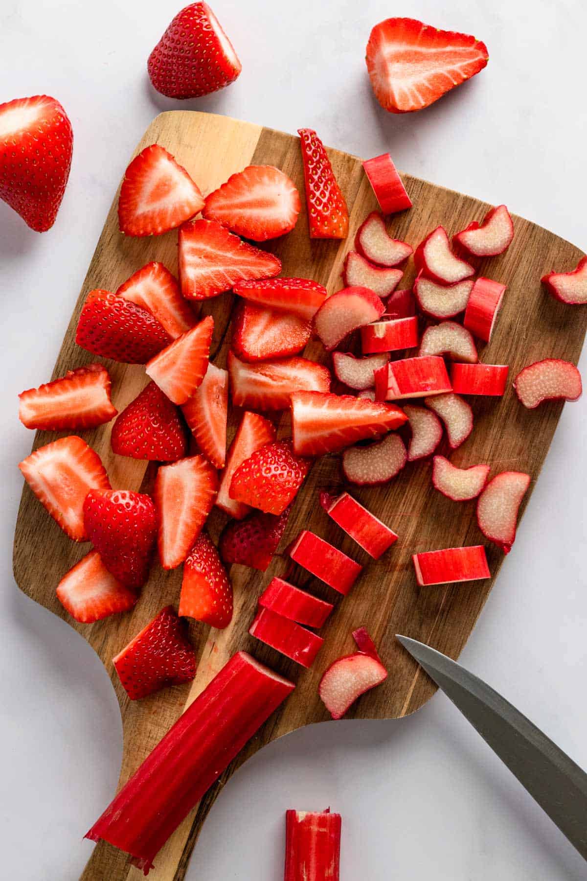 fresh strawberries and rhubarb on a wooden cutting board