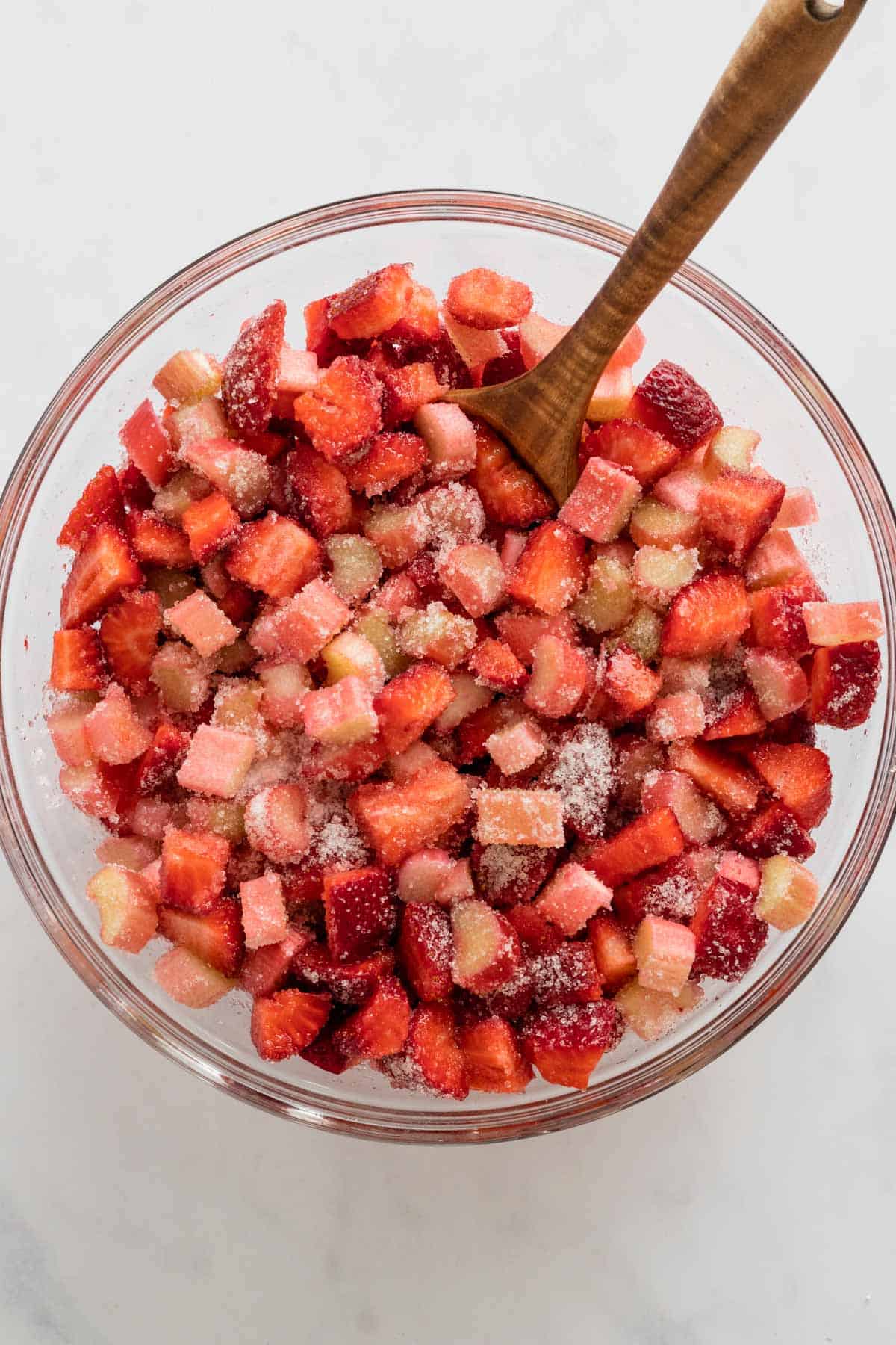 diced strawberries and rhubarb in mixing bowl with sugar and lemon