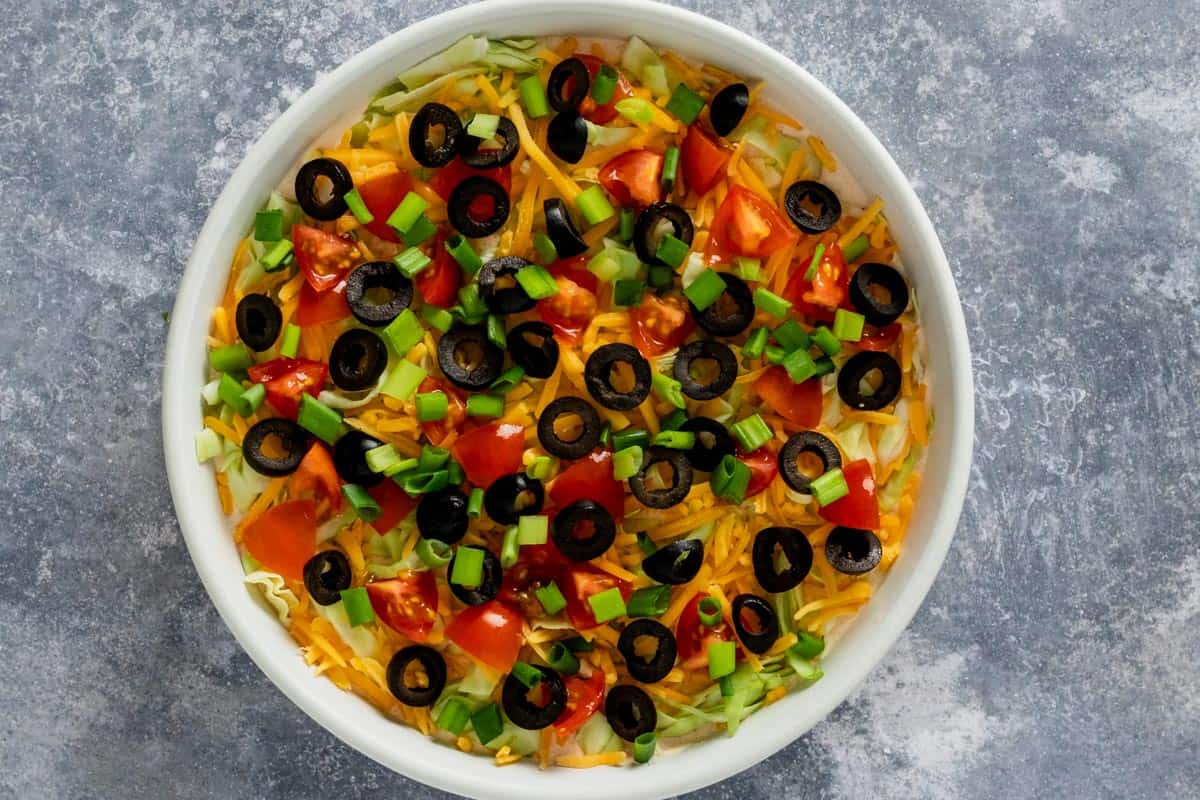 taco dip with toppings in serving dish
