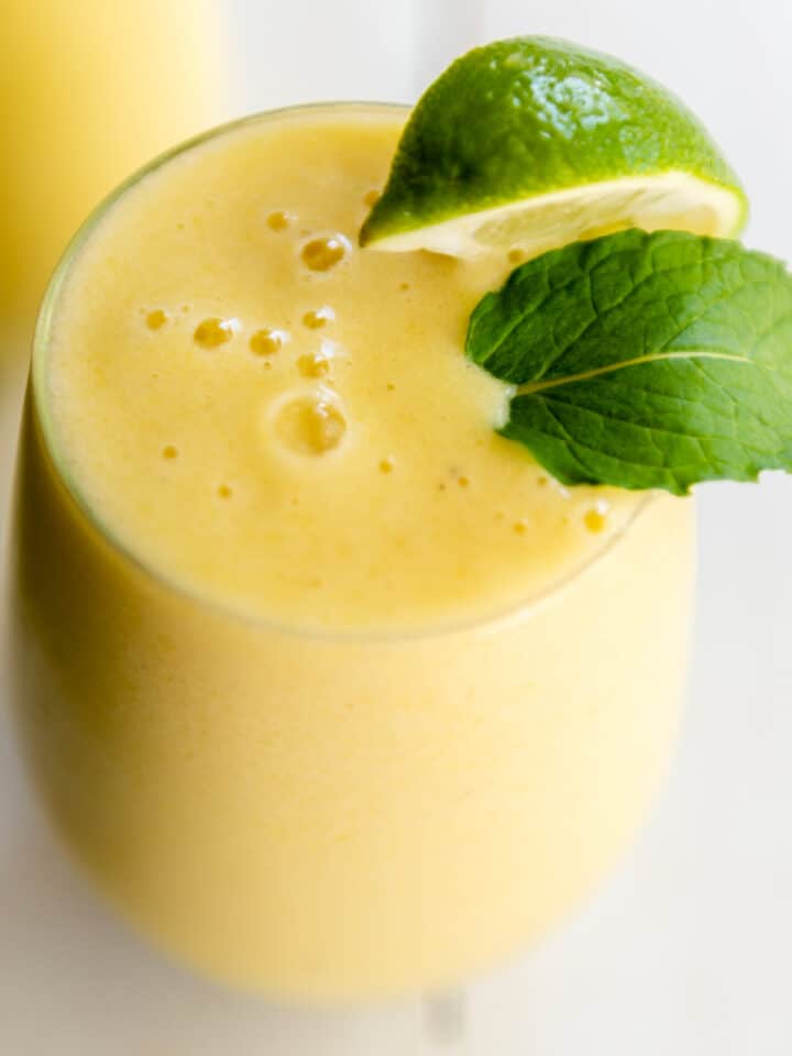 tropical smoothie in a tall glass with mint and lime wedge