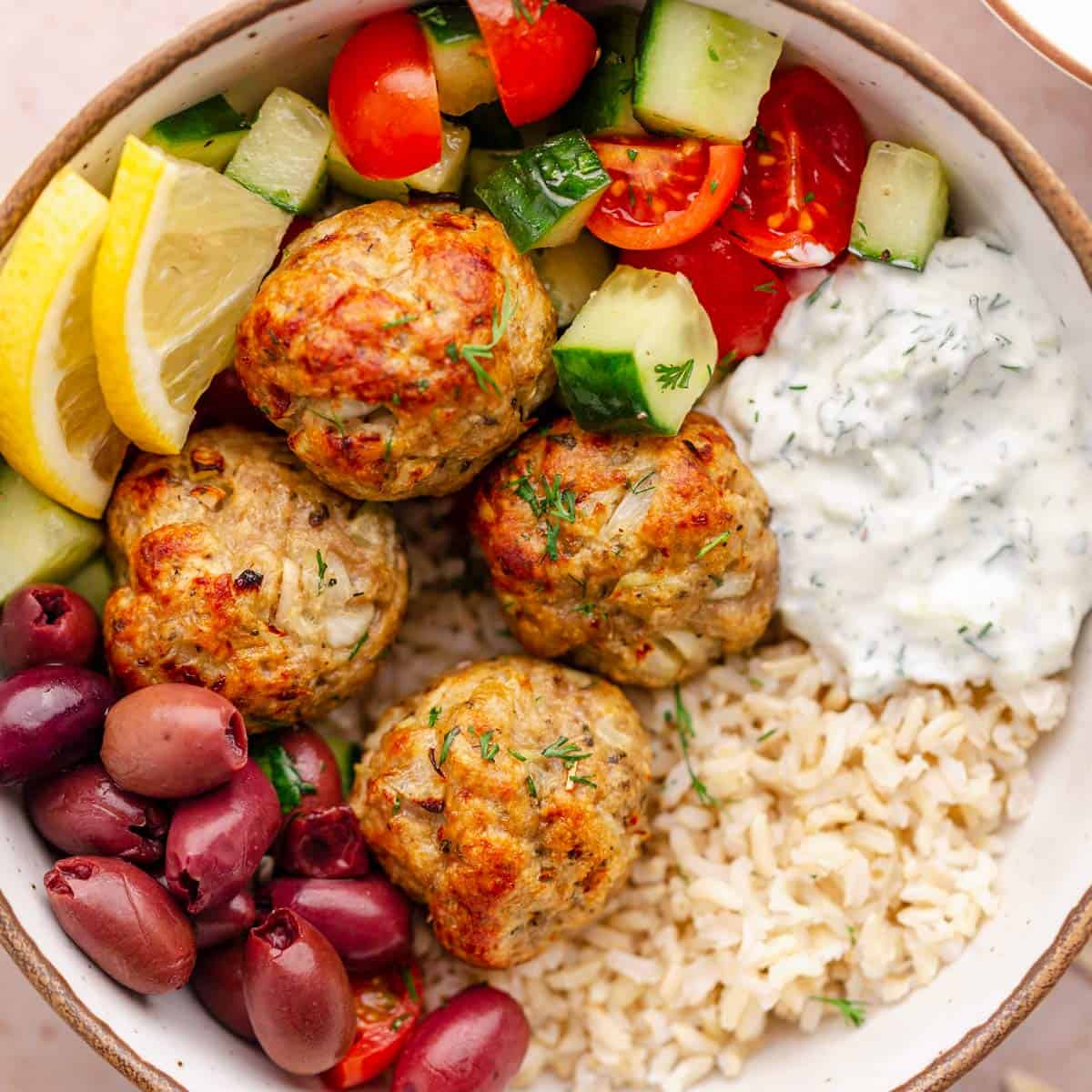 turkey meatballs with brown rice, lemon, tzatziki sauce and cucumber tomato salad.