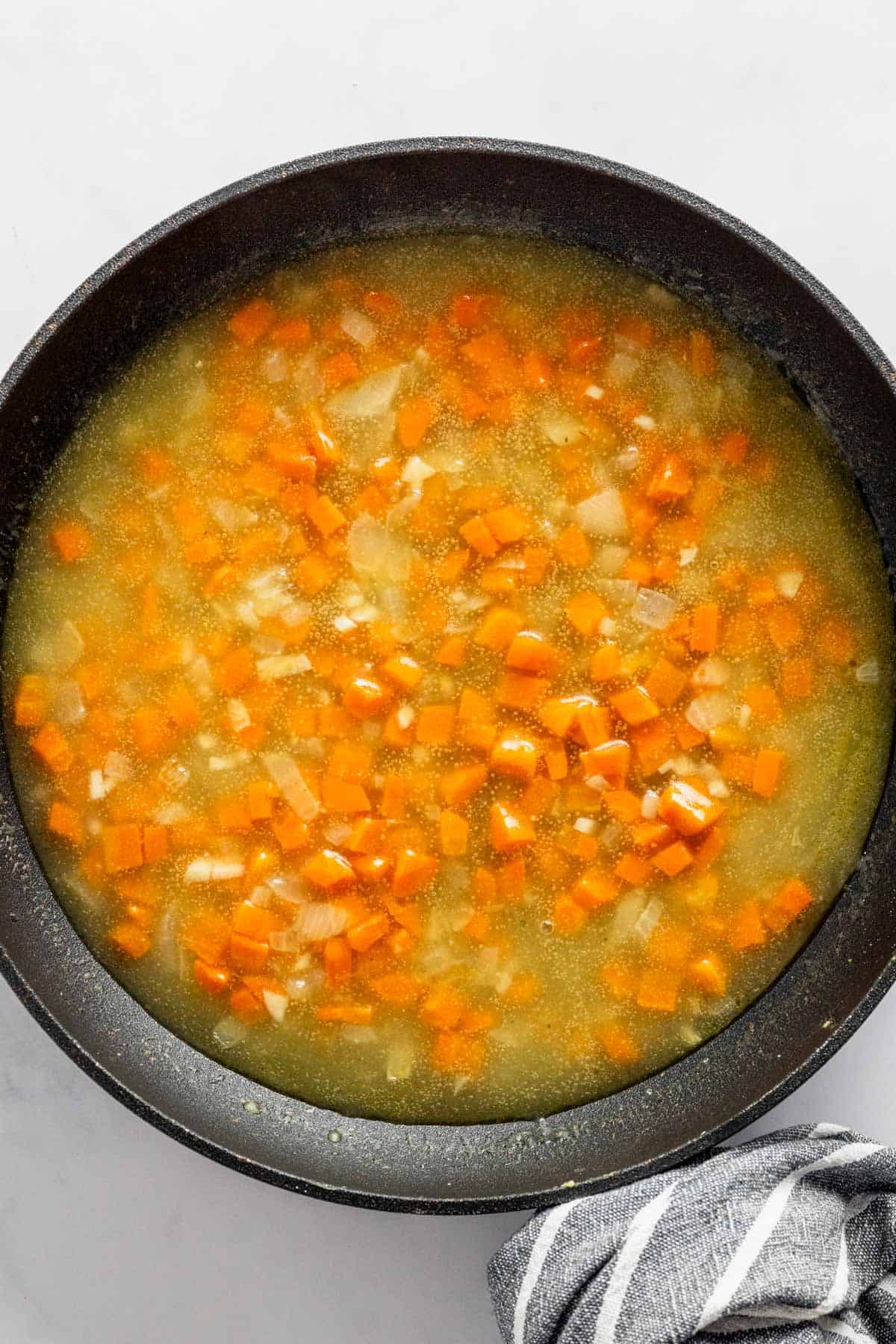 broth and carrots simmering in skillet.