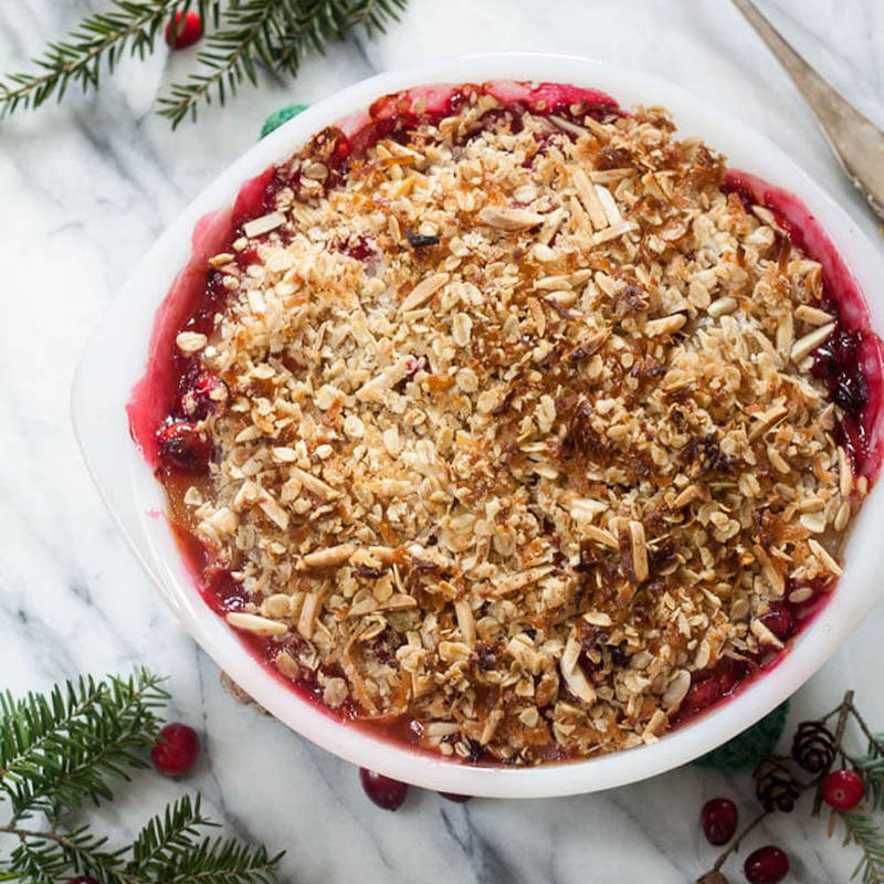 Apple Cranberry Crisp Cake oin a round plate with christmas decorations